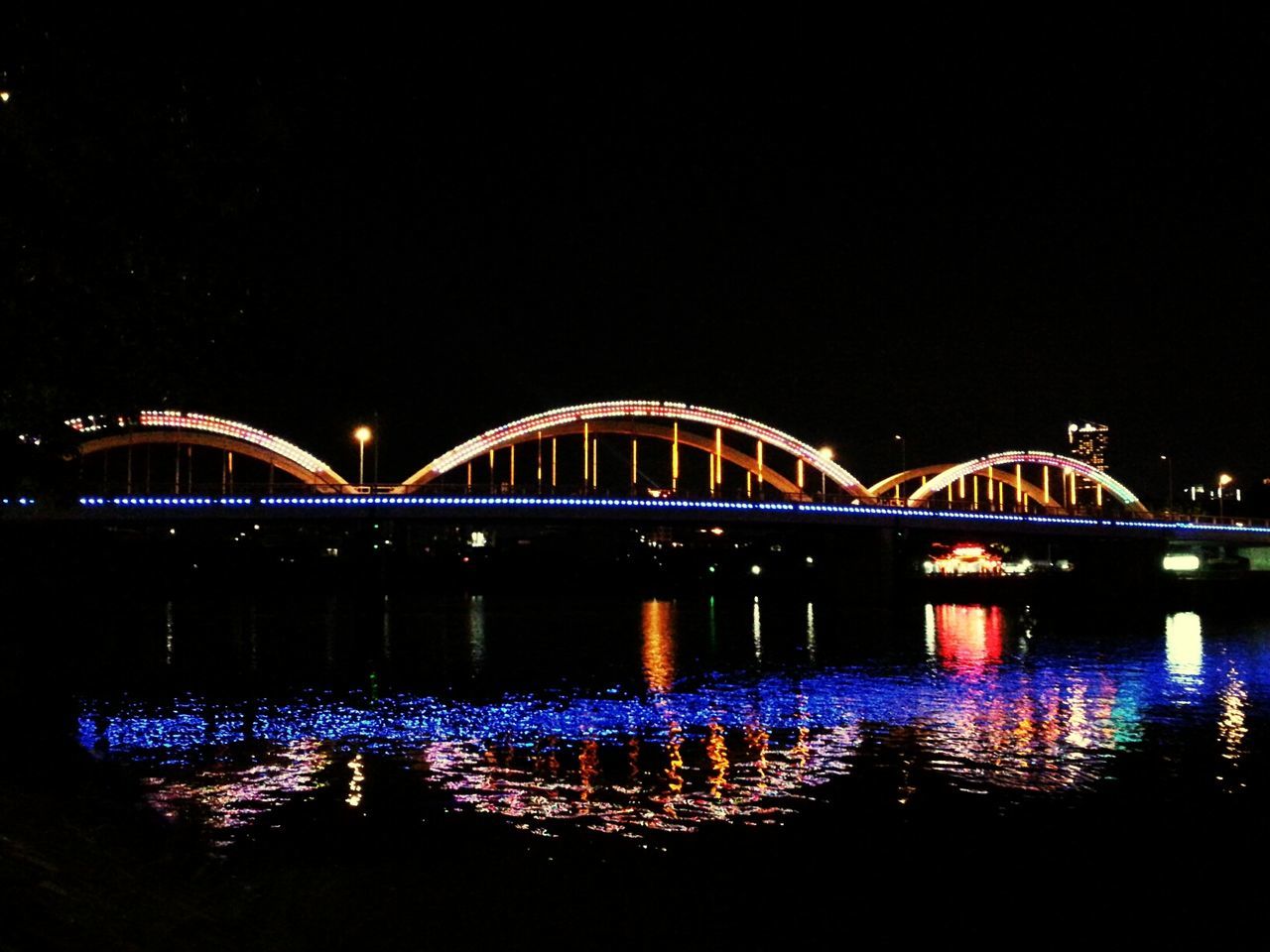 illuminated, night, water, reflection, connection, architecture, built structure, bridge - man made structure, river, waterfront, clear sky, bridge, copy space, engineering, arch bridge, lighting equipment, city, arch, travel destinations, light