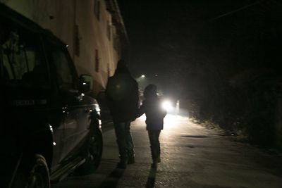 Rear view of silhouette man on road at night