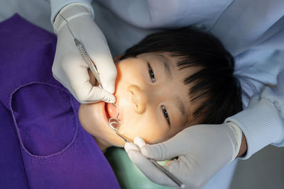 Hand of doctor dentist is working on the teeth of asian little kid in dental clinic