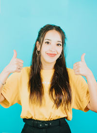 Portrait of young woman against blue background