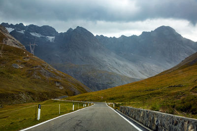 Road leading towards mountains against sky