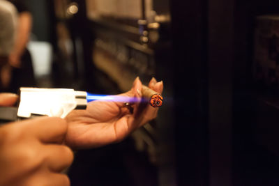 Hands of woman burning cigar with lighter