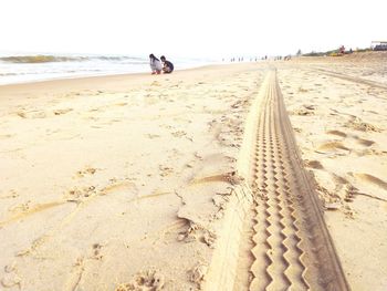 Rear view of people walking on beach against clear sky