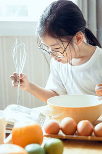 Girl reading book while preparing food at home