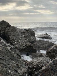 Rocks on beach against sky during sunset