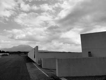 Empty road by building against sky
