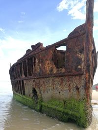Abandoned boat by sea against sky