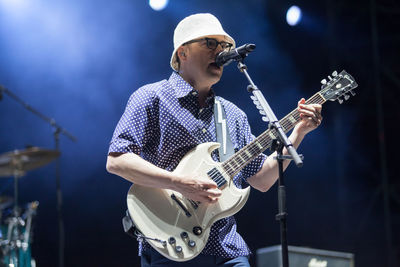 Young man playing guitar at music concert