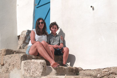 Family sitting against wall, blue doors 