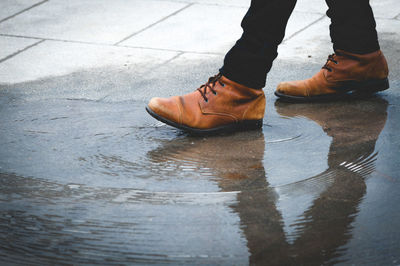 Low section of man walking on wet footpath