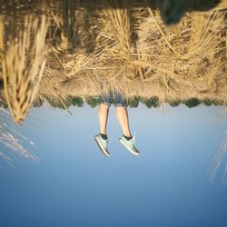 Upside down image of person on field against sky