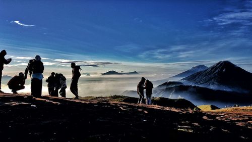 People standing on mountain against blue sky