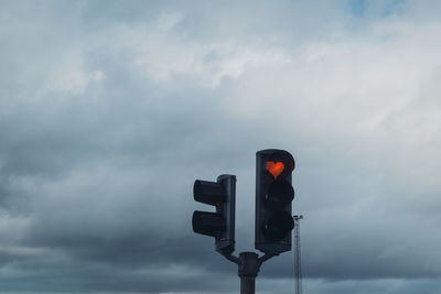 Low angle view of heart shape on road signal against sky