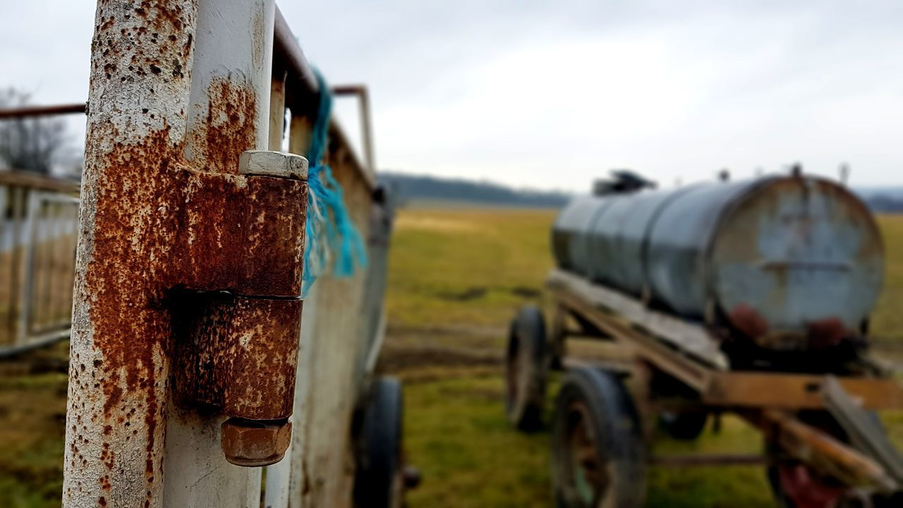 focus on foreground, land, day, transportation, metal, rusty, nature, mode of transportation, no people, field, sky, land vehicle, outdoors, old, plant, agriculture, deterioration, close-up, run-down, decline, wheel