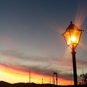 Low angle view of illuminated street light against sky during sunset