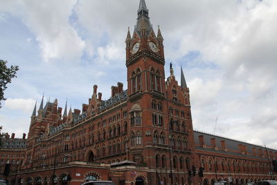 Low angle view of st pancras railway station against cloudy sky