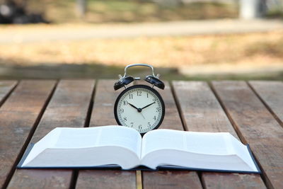 Close-up of alarm clock on book at table