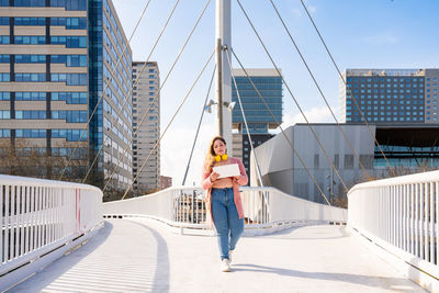 Young woman holding placard walking on footbridge