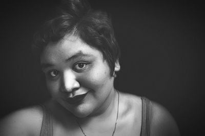 Close-up of young woman against black background