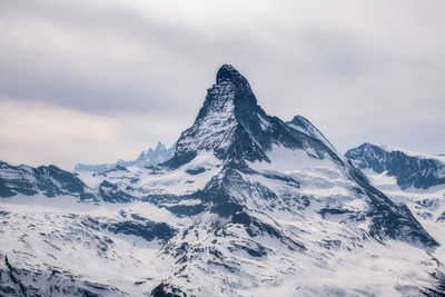 Scenic view of snowcapped mountains against cloudy sky