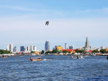 Nautical vessel on sea by city against sky