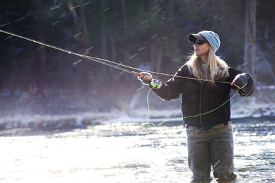 Determined woman fishing in lake on sunny day