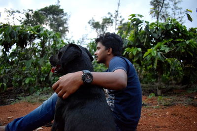 Rear view of woman with dog against trees