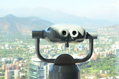 Close-up of coin-operated binoculars against cityscape