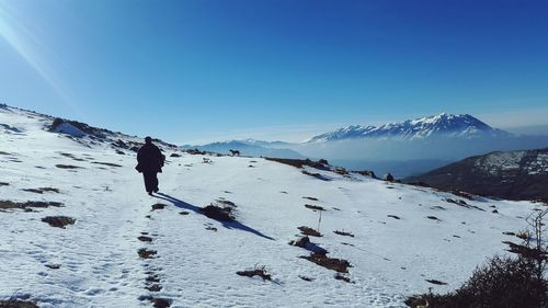 Full length of man on snowcapped mountains against clear blue sky
