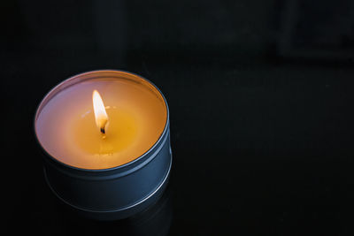 Close-up of lit candle against black background