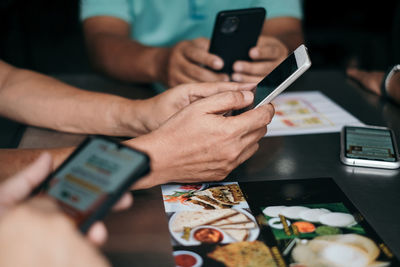 Midsection of man using mobile phone on table