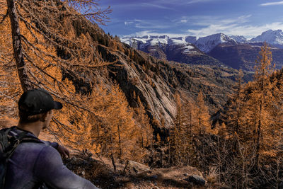 Rear view of man relaxing on rock in winter