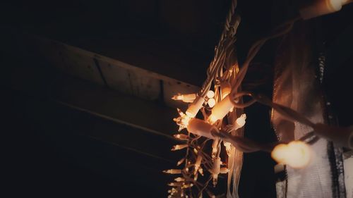 Low angle view of illuminated lighting equipment hanging at night