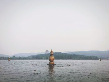 Sculpture in lake against clear sky