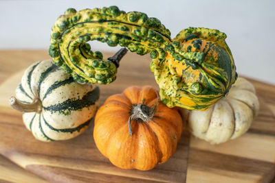 A selection of mini pumpkins balancing on top of each other on a wooden chopping board