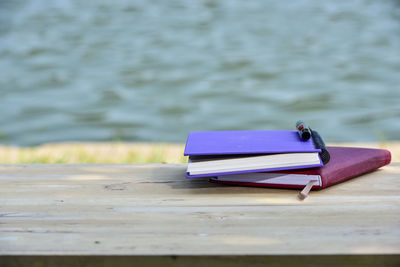 Close-up of book on table against pier over lake