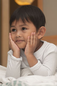 Close-up of cute boy sitting on bed at home