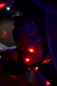 Close-up of a young woman. she is sitting in the room with red light. 