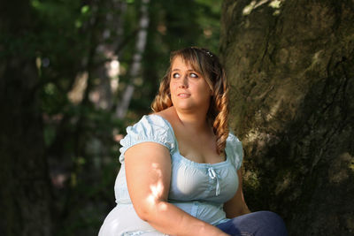 Young woman standing on tree trunk