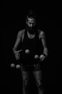 Portrait of man standing against black background