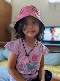 Portrait of child sitting at home wearing pink hat