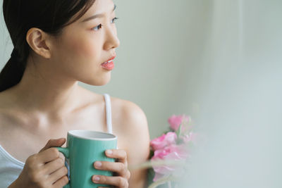 Woman looking away while drinking coffee at home