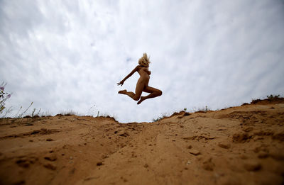 Low angle view of man jumping on beach