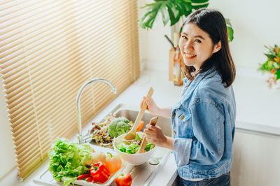 Portrait of smiling woman preparing food at home