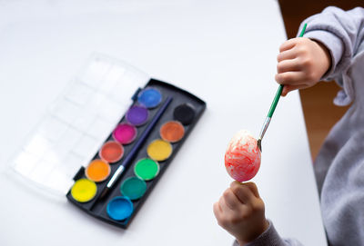 Close up of childrens hands holding easter egg and painting it with brush. preparation for easter.