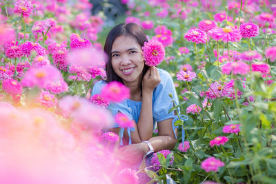 Portrait of smiling young woman with pink flowers