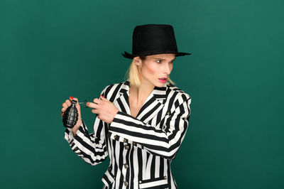 Portrait of young woman standing against gray background