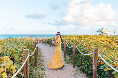 Rear view of woman standing by railing against sea
