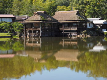 House by lake against trees and houses