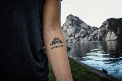 Low section of person with text on lake against mountain
